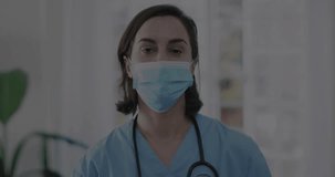 Animation of medical icons over caucasian female doctor wearing face mask in hospital. Global medicine, healthcare, hospital and digital interface concept digitally generated video.