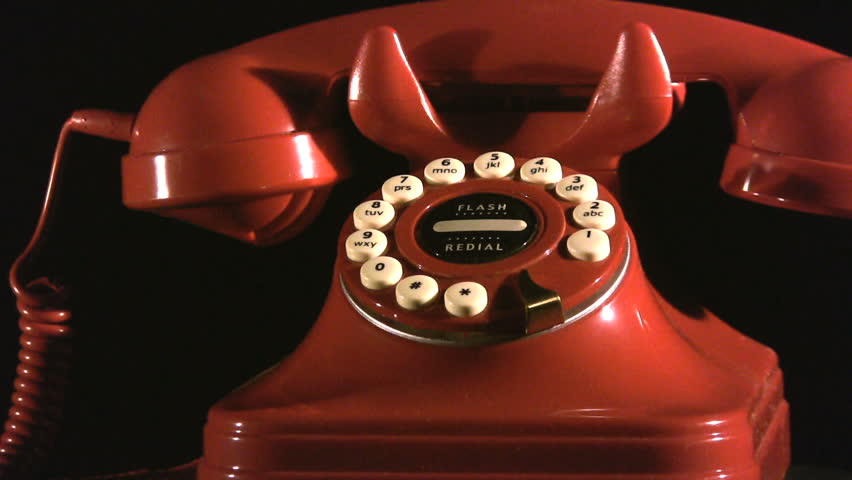 A vintage red phone on a turn table.