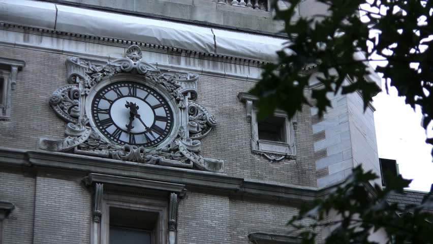 A clock on an old building in NYC.  Leaves blowing in the foreground.  3 views