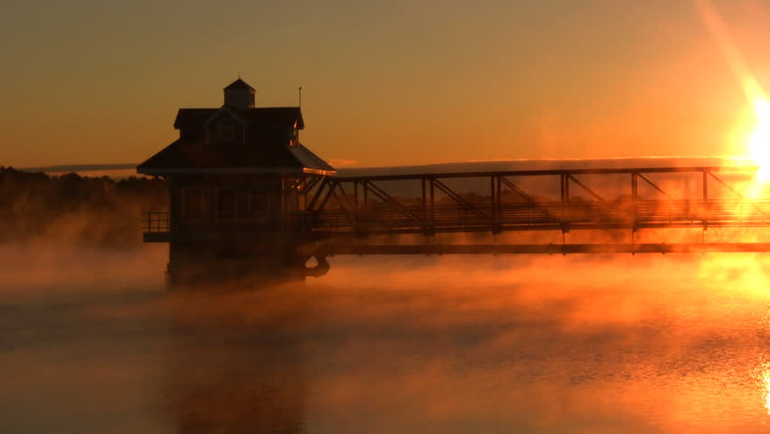 Lake Pavilion on water at sunrise.  Fog and Mist moves across the lake.