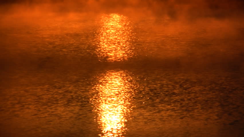 Reflection of the sun during sunrise coming off of a lake.  Colored mist or fog