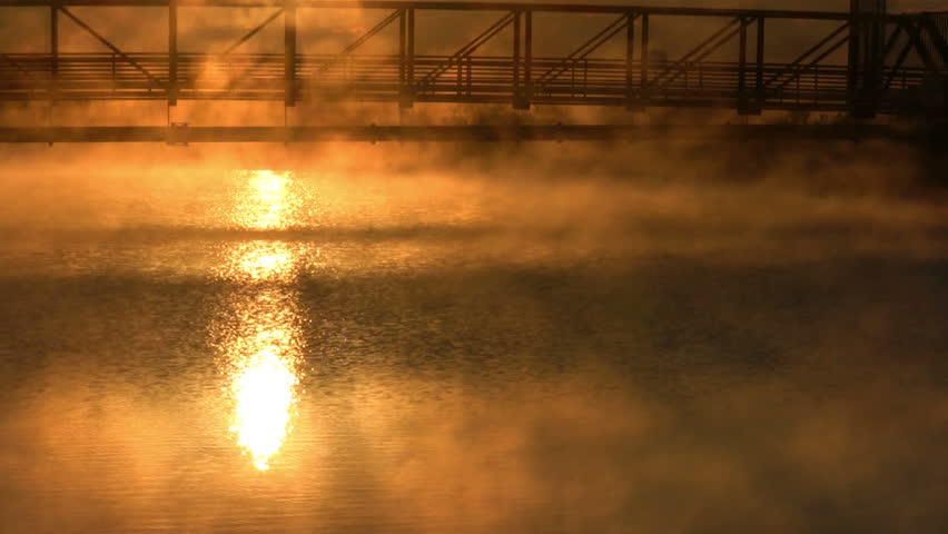 A sunbeam shooting through a bridge onto the lake water. 