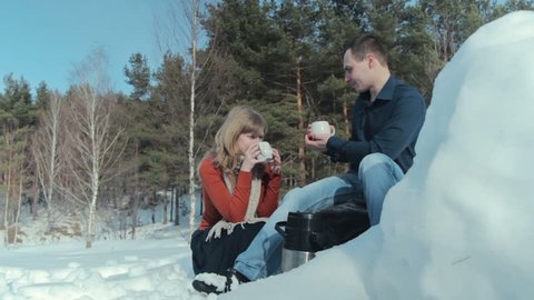 Young couple in love on a winter vacation enjoying the nature and drinking hot tea