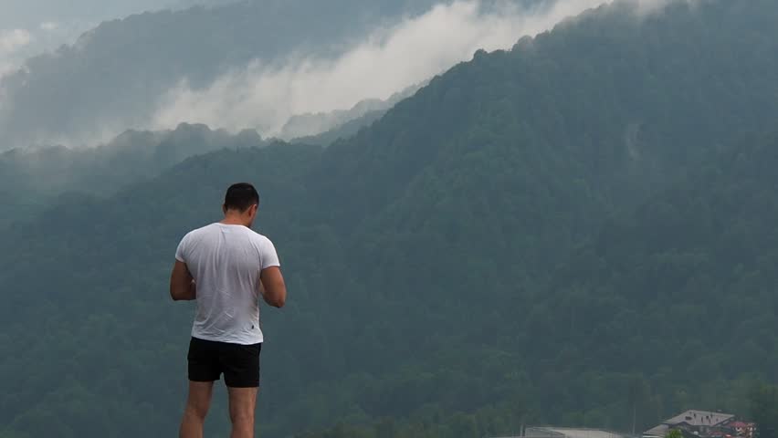 Man looking at the mountains and spreads his hands