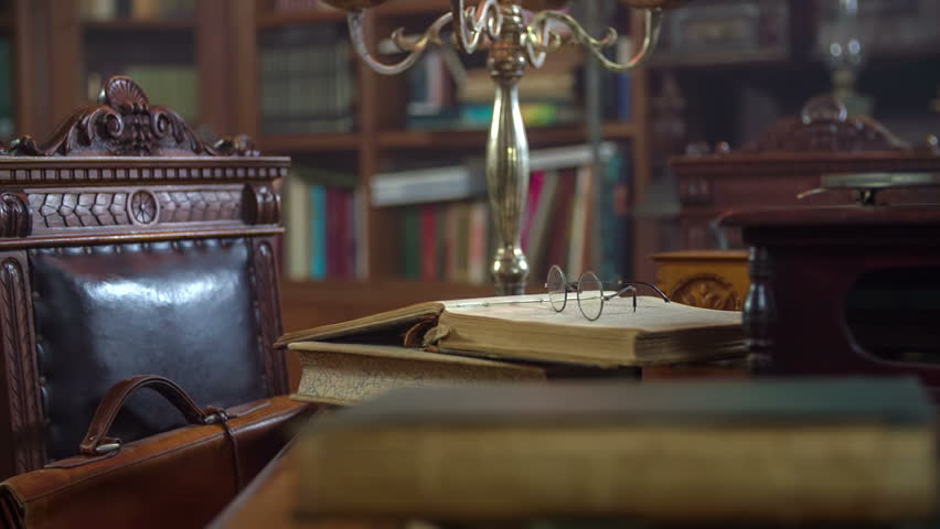 Camera flaying across the the table full of vintage books and candles, close up footage taken in RAW.