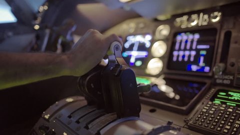 Detail shot of airline pilot pushing throttle forward and then pulling back in the cockpit of a jumbo jet.  Side view, hand-held camera, originally recorded in 4K.