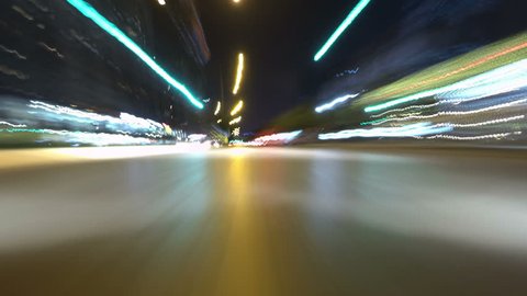 Time-lapse POV shot of a car driving through the city at night. Camera mounted on car's bumper facing forward.