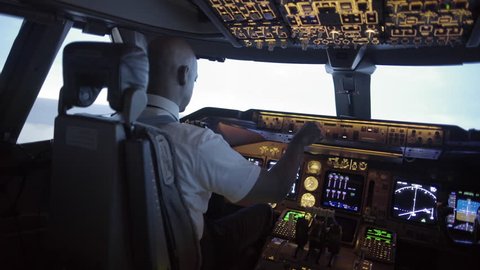 Dramatic angle from rear of 747 cockpit as African American pilot makes a long turn over an area of northern California, USA. Stabilized hand-held camera, mid shot, originally recorded in 4K at 30ps