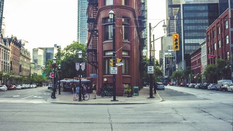 TORONTO, CANADA - CIRCA JULY 2015: Timelapse of the famous flat iron Gooderham Building landmark with traffic and streetcars passing at the busy city intersection in Toronto, Ontario, Canada.