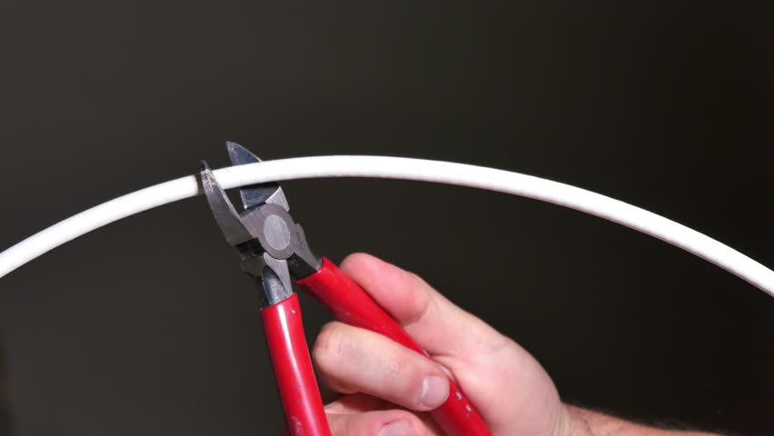 A hand cuts a coax cable television cord. Royalty-Free Stock Footage #11158646