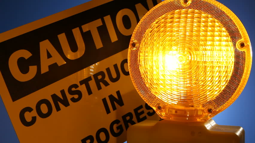 A caution sign is lit up by a blinking yellow warning light