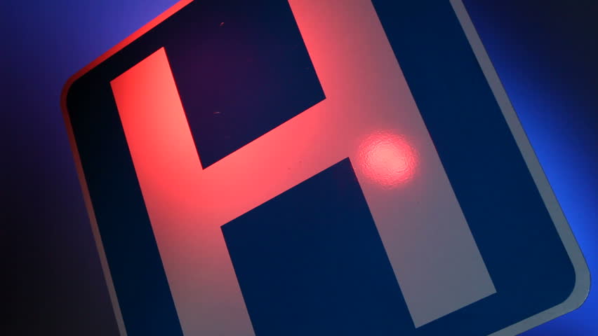 A close up of a hospital sign with flashing red and blue lights reflected on the