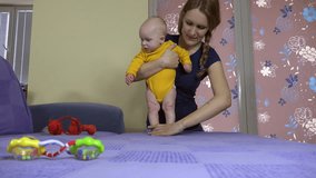 mother make with baby daughter sport exercise train child muscle on sofa. Baby care and motherhood. Static tripod shot. 4K UHD video clip.