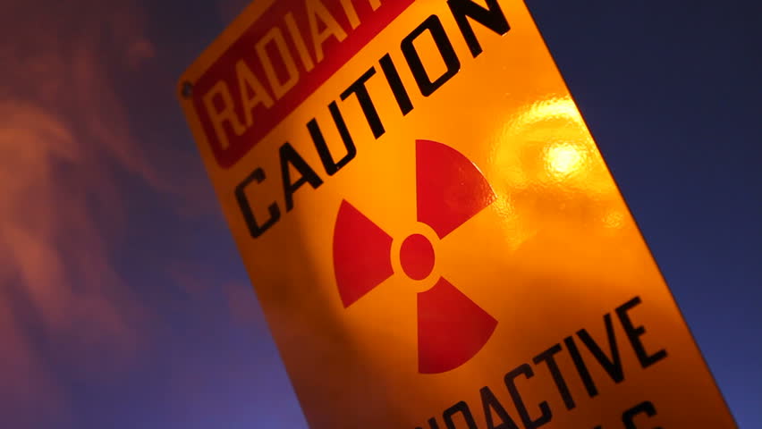 A close up of a radiation warning sign with flashing lights reflected on the
