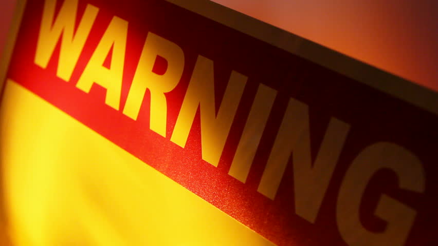 A close up of a warning sign with flashing lights reflecting on the sign