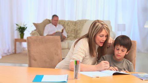 Grandmother helping her grandson to do his homework in the living room