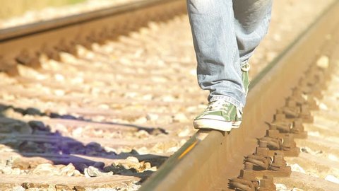 A footage of a teenager strutting along the railway in sneakers