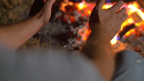 4 in 1 video! The man sit near bonfire and heat hands. Close up view. Shot with Red Cinema Camera