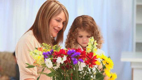 A little girl making a bouquet of flowers with her grandmother in the living room