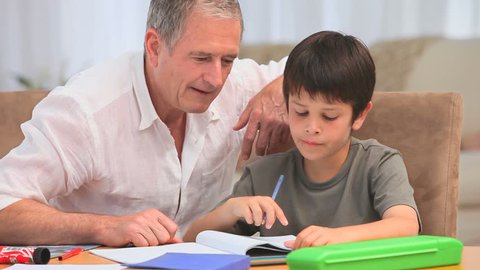 Little boy doing his maths homeworks with his grandfather