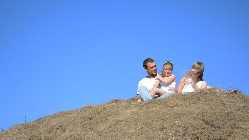 young family on a haystack in summer father mother and daughter