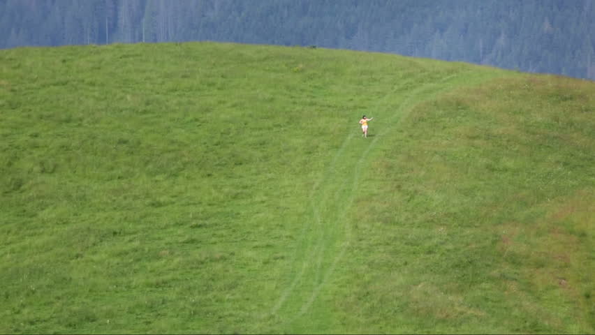 Female make selfie far on mountain meadow. Small people.