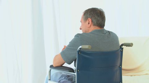 A man in a wheelchair lookink through the window