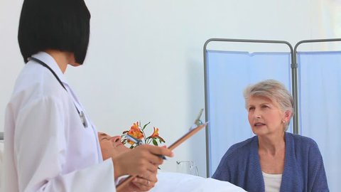 An asian nurse talking to the wife's patient at the hospital