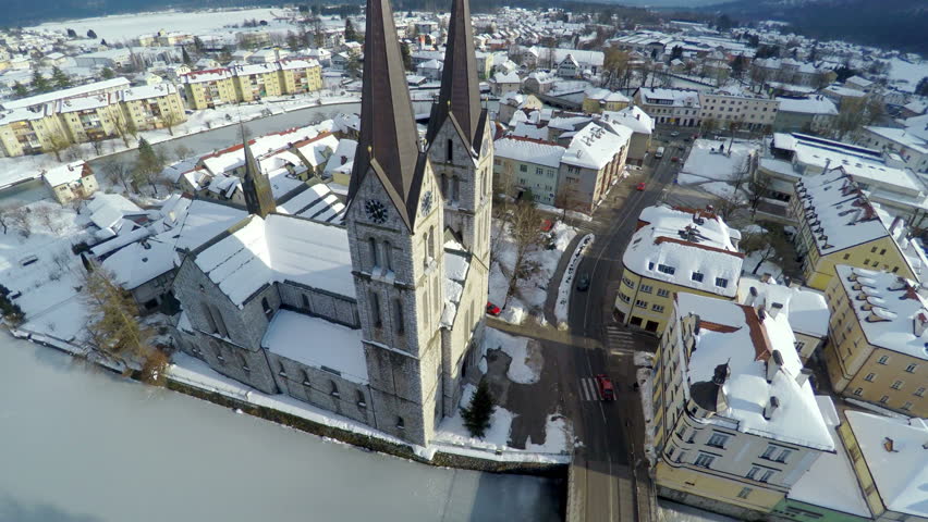 Trough the middle of the village is going a frozen river and the village is covered with snow, helicopter camera footage.