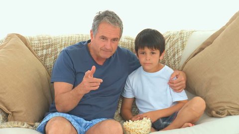 Mature Caucasian man and his grandson watching a match on tv in the living room