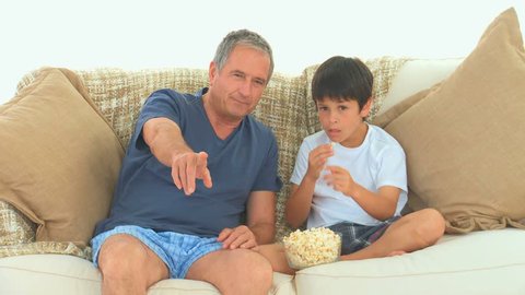 Caucasian grandfather and his grandson watching a match with popcorn
