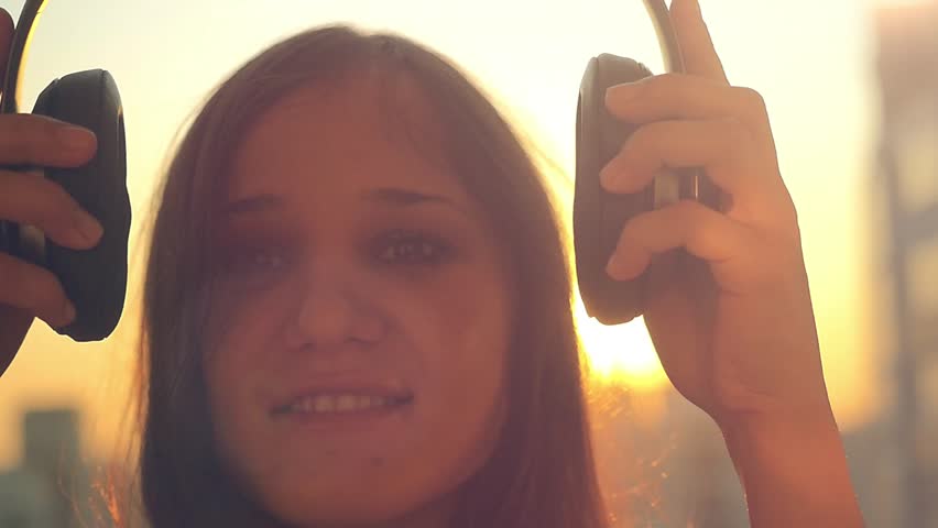 Slow motion of Young woman get dressed headphones listening to music  at city sunset and dancing. 1920x1080