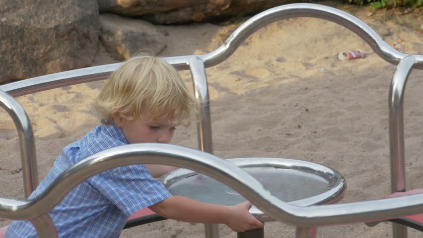 Little boy with blond hair spinning on the carousel