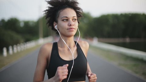 Woman running at sunrise listening to music with earphones