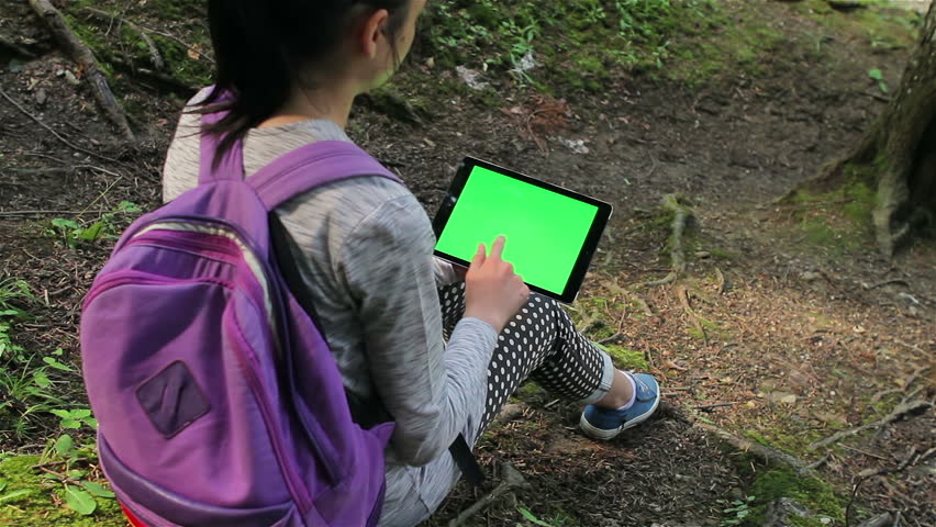 Tourist girl using a tablet pc with copy space in the forest.