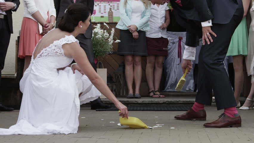 A groom sweeps a broken plate into a dustpan.  This is a tradition in the Czech Republic during a wedding. In slow motion.
