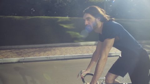 young handsome man rides a bicycle in the park slow motion