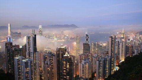 Time lapse Sunset over Hong Kong skyline from famous Peak View at night. Fog comes into the city. 