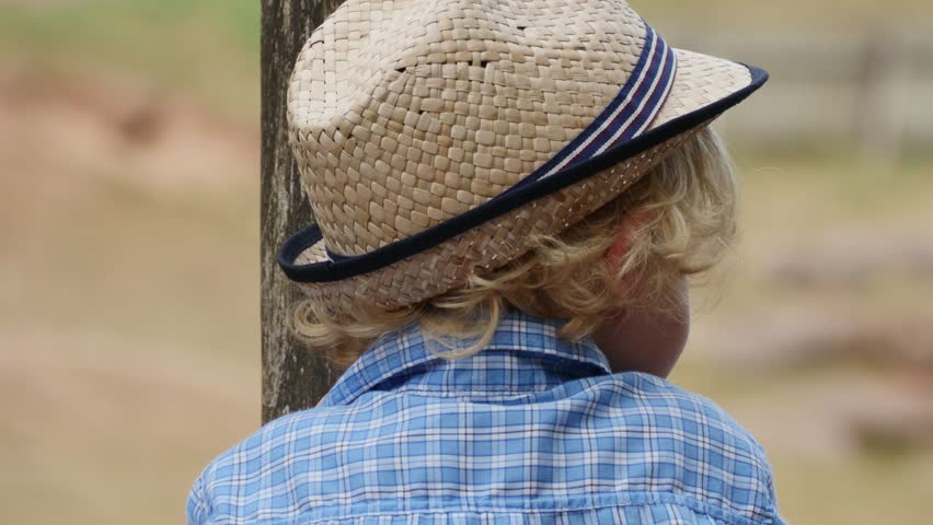 Curly blond little boy in a hat having fun