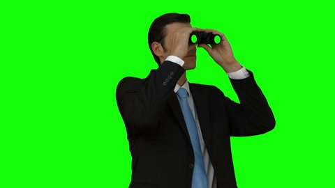 Businessman looking through binoculars on green screen background