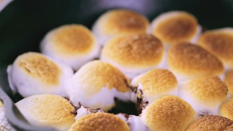 Smores dip prepared with large marshmallows in cast iron pan.
