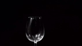 Pink wine pouring into glass on black background