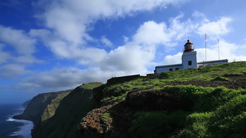 Lighthouse on cape and cloudscape over rocky coastline  