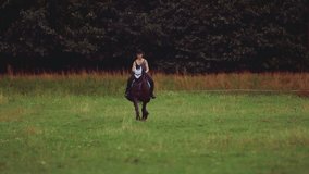 Woman Riding Horse On Ranch. Full length of young woman riding horse on ranch. 
Young girl riding horseback, passing in front of the camera

