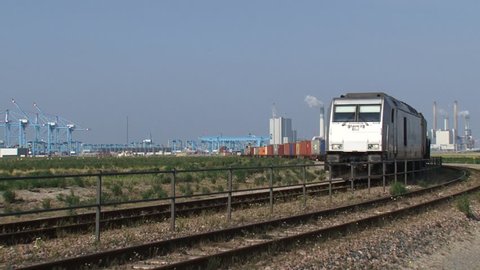 MAASVLAKTE II, ROTTERDAM - AUGUST 2015: freight train approaching in bend, seaport and container terminal APMT in background. The railway, connecting Rotterdam with China, is called the new silk road