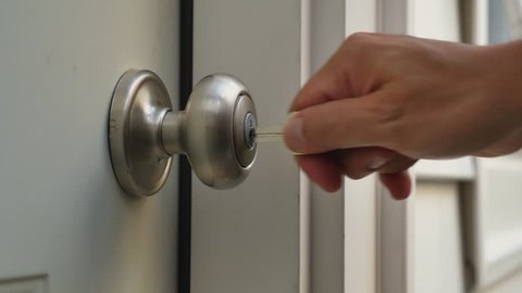 A man unlocks a house's door and enters.
