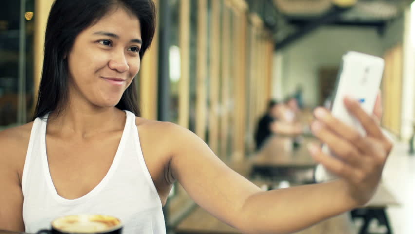 Young woman taking selfie photo with cellphone in cafe 
