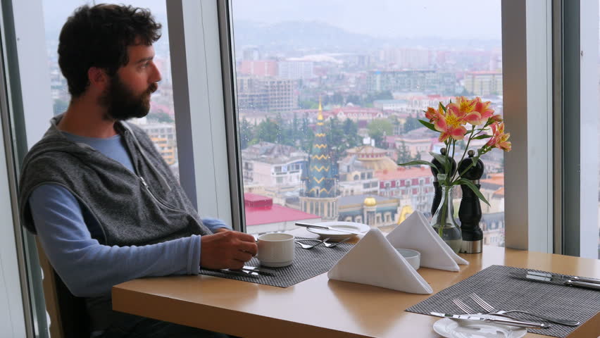 casual man drinking coffee, high rise skyscraper, batumi, georgia background