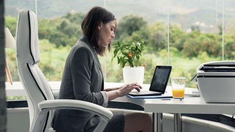 Young businesswoman finish working on laptop and drinking beverage in office
