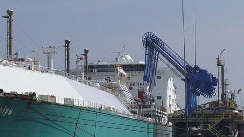 ROTTERDAM - AUGUST 2015: LNG tanker Gaselys berthed and unloading at GATE (Gas access to Europe) terminal + permanently cooled unloading arms connected - medium shot